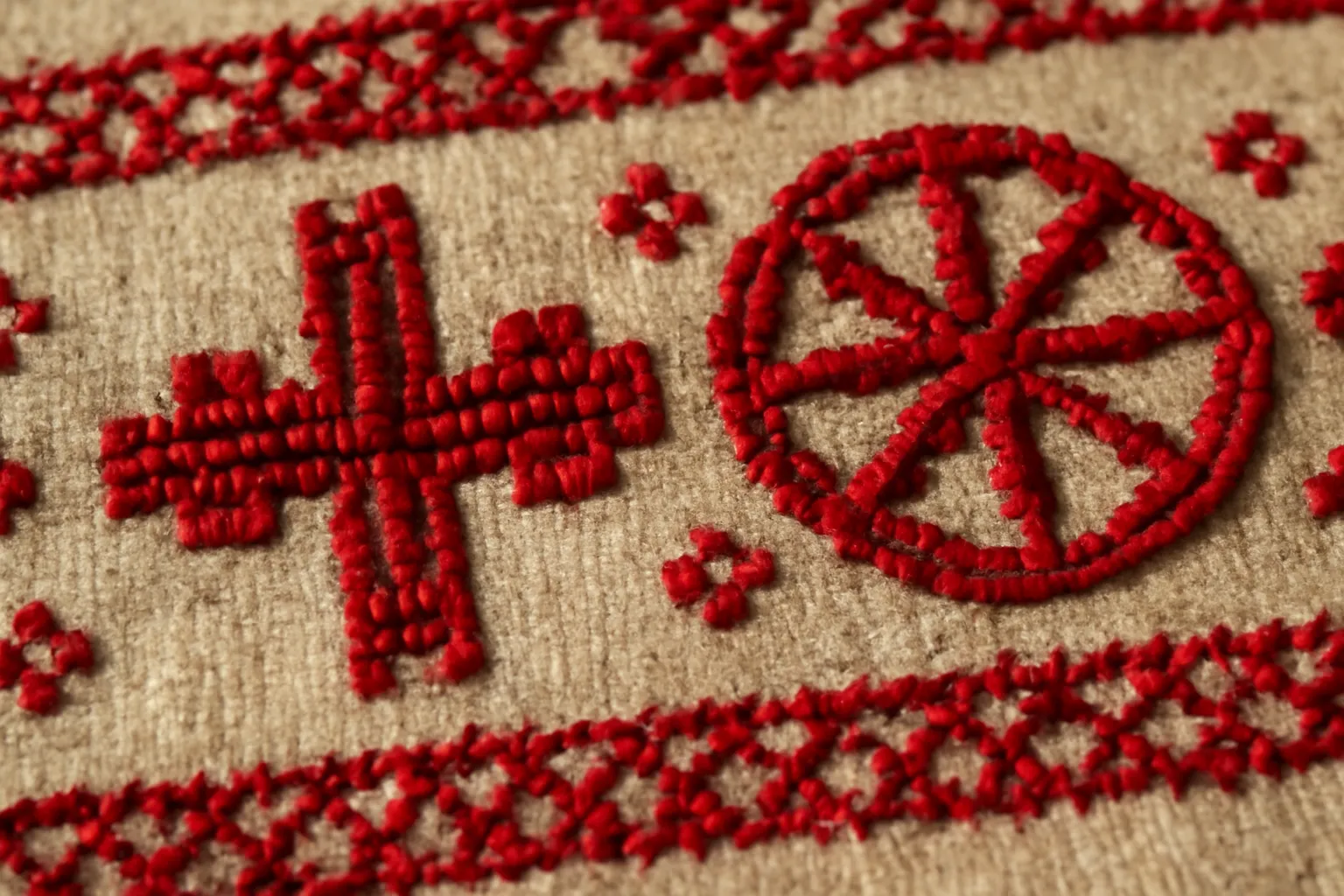Textile brodé traditionnel slave avec motifs géométriques de croix et roue solaire en fils rouges