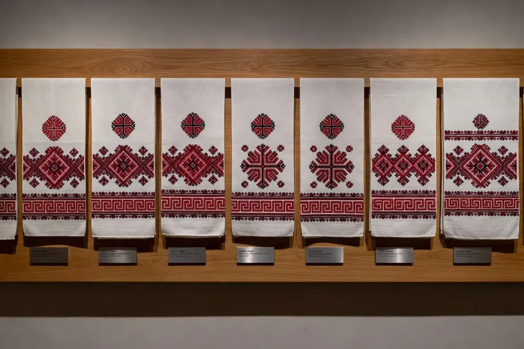 Collection de rushniki biélorusses avec motifs régionaux différents exposée dans un musée